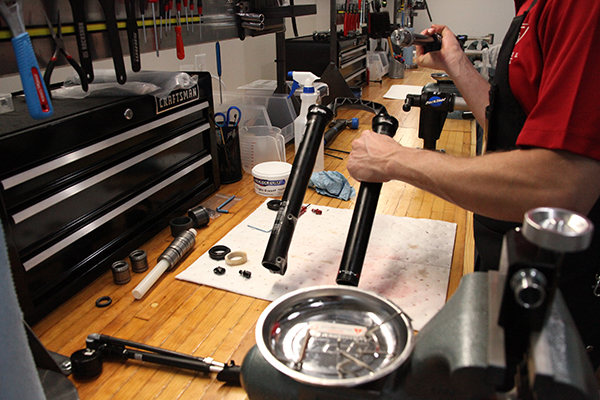 Technician servicing bike suspension in repair shop